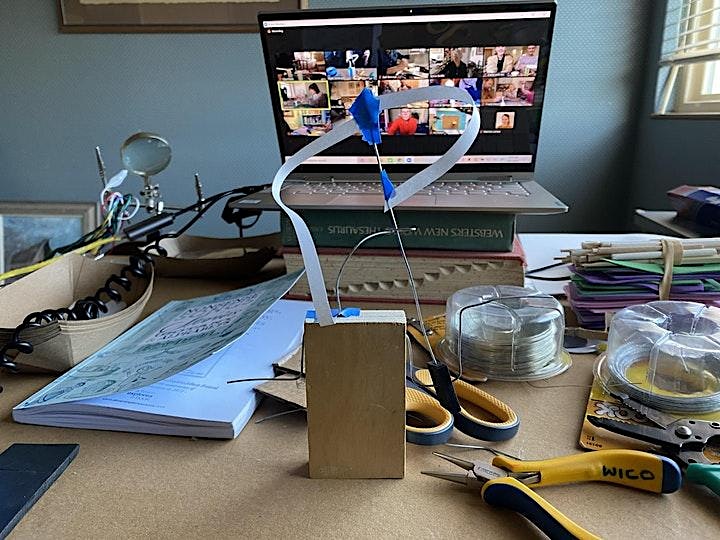 Tools, books and an automata in progress with a multi person zoom call on the laptop behind.